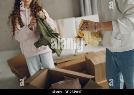 Felice giovane famiglia coppia uomo e donna disimballaggio scatola dopo aver spostato scatole di cartone in un nuovo appartamento di casa Foto Stock
