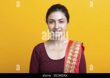 Ritratto di giovane donna indiana adulta su sfondo giallo sari Foto Stock