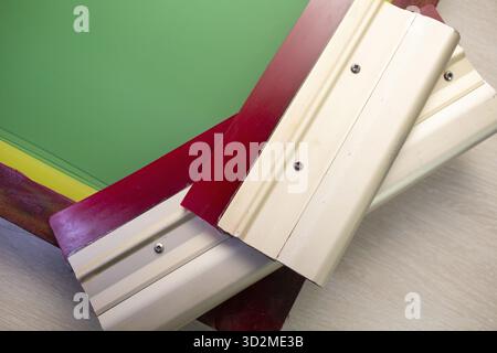 Serigrafia serigrafica processo di stampa presso la fabbrica di abbigliamento. Telaio stencil e squeegee Foto Stock