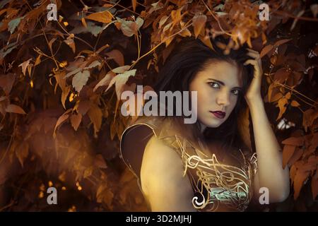 Forest Fairy, Bella bruna donna che indossa oro e rame corsetto in dea e guerriero pone. fantasia e immaginazione concept Foto Stock