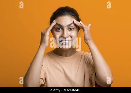 Primo piano ritratto della giovane donna indiana americana che tocca la pelle del viso le mani e che fa autogyoga viso ginnastica massaggio Foto Stock