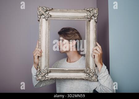 Millenial giovane artista con capelli biondi su una cornice dorata Foto Stock
