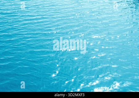 Sfondo turchese con consistenza dell'acqua increspata. Piscina a ondulazione di acqua blu brillante astratta Foto Stock