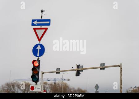 Intersezione urbana con semaforo illuminato, frecce direzionali e segnale di snervamento che mostra l'organizzazione stradale della città, la sicurezza dei trasporti e la moder Foto Stock