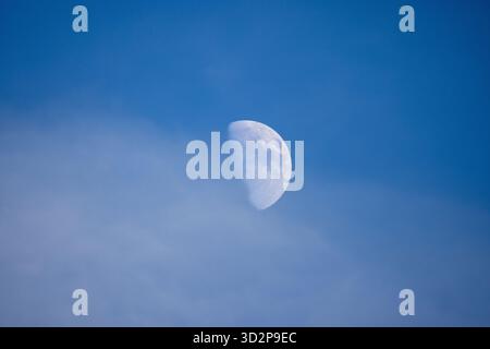 Primo piano della Luna alla luce del giorno contro un cielo blu che mostra crateri visibili e dettagli della superficie Foto Stock