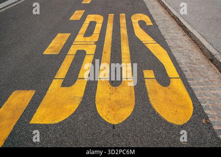 Segnaletica gialla della fermata dell'autobus verniciata su fondo stradale in asfalto nero, vista ad angolo alto Foto Stock