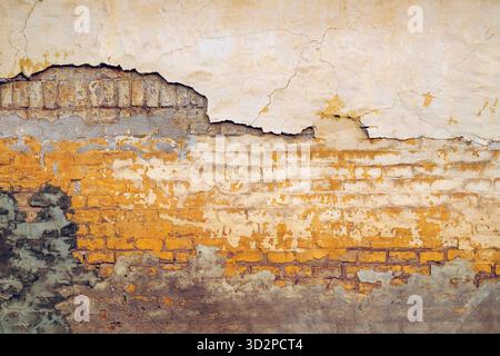 Trama dettagliata della vecchia parete gialla che mostra crepe, struttura dei mattoni e patch di riparazione del cemento, perfetta per lo sfondo o lo spazio di copia. Immagine orizzontale. Foto Stock