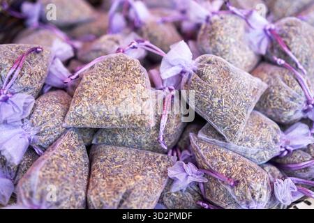 Vista ravvicinata di numerosi piccoli sacchetti di organza color lavanda pieni di boccioli di lavanda essiccati, pronti per la vendita in pile. Foto Stock