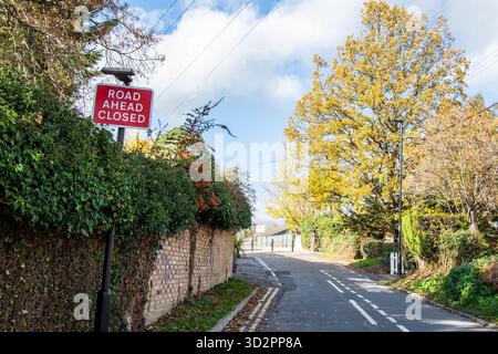 Cartello rosso "Road Ahead CLOSED" posto a lato della strada, che avverte i conducenti di una chiusura o di una deviazione su una strada del Regno Unito. Foto Stock