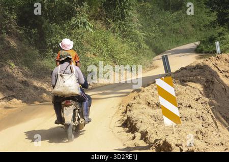 Due persone in moto viaggiano su una strada rurale non asfaltata difficile. Viaggio impegnativo attraverso il paesaggio montano remoto in Asia, mostrando un'avventura Foto Stock