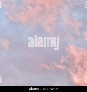 Un'atmosfera da sogno in cui una massa drammatica di nuvole di rosa e pesca si illumina contro una malva pallida e il cielo blu durante il tramonto o l'alba, riempiendosi Foto Stock