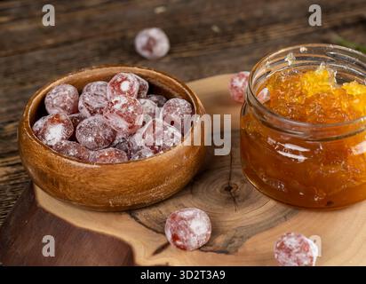 marmellata d'arancia composta da arance e agrumi ed essiccata in sciroppo di zucchero, frutta kumquat intera in polvere bianca, un vaso di vetro con marmellata d'arancia dolce è acceso Foto Stock