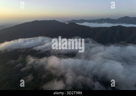Serena vista aerea sulla catena montuosa all'alba. il tranquillo mare di nuvole riempie la profonda valle sottostante, creando un'atmosfera tranquilla e maestosa Foto Stock