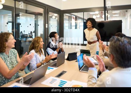 Team aziendale eterogenei che applaudono una presentazione di successo Foto Stock