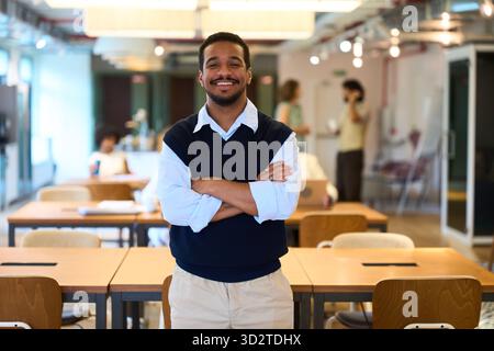 Sorridente giovane latino in piedi fiducioso nell'ufficio di coworking Foto Stock
