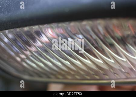 Dettaglio ravvicinato dei fari dell'auto che mostrano un'intricata struttura scanalata e un motivo di lenti trasparenti in plastica o vetro. moderna vista astratta di un'auto Foto Stock