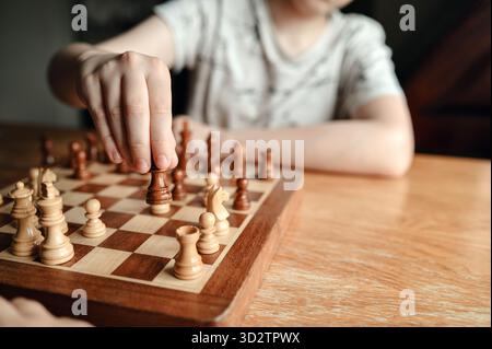 Primo piano della mano del ragazzo che muove un pezzo da scacchi. Foto Stock