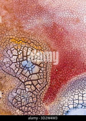 Veduta aerea di un mosaico di terra incrinata dipinto con vivaci sfumature di ruggine, crema e azzurro, inciso sul paesaggio geotermico e sulle aree geotermiche Foto Stock