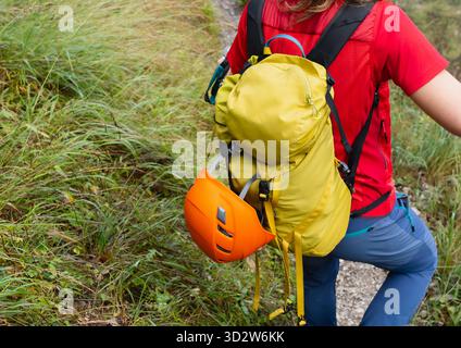 Escursionista che indossa una giacca rossa, zaino giallo con casco arancione da arrampicata. Attrezzatura di sicurezza per trekking in montagna per avventure all'aperto Foto Stock