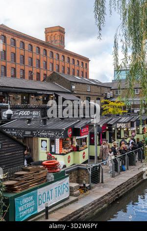 Persone ai chioschi di cibo di Camden Market, una popolare attrazione turistica di Camden Town, Londra, Inghilterra, Regno Unito, con l'Interchange Building Foto Stock