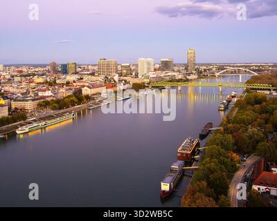 Bratislava, Slovacchia - 18 ottobre 2025: Vista serale dello skyline della città di Bratislava con edifici illuminati e un fiume Danubio che riflette le luci. Foto Stock