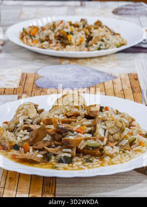 Un piatto di riso con carne e verdure. Il riso è marrone e la carne è marrone. Le verdure sono arancioni e verdi Foto Stock