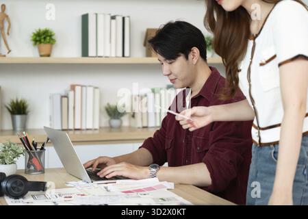 Due designer che collaborano a un progetto di interfaccia utente, concentrandosi su schizzi e mockup digitali in uno spazio di lavoro creativo Foto Stock