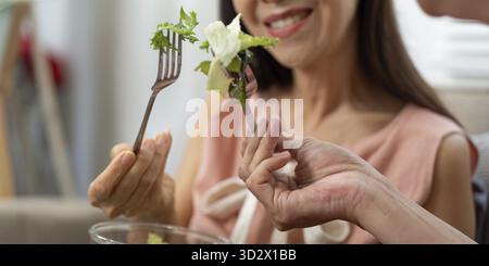Una coppia di anziani condivide un momento di gioia, brindando con bicchieri d'acqua, sottolineando il benessere e l'idratazione nella loro vita quotidiana Foto Stock