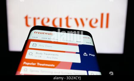 Stoccarda, Germania - 10-25-2025: Telefono cellulare con sito web della società di prenotazioni benessere Treatwell sullo schermo davanti al logo. Foto Stock