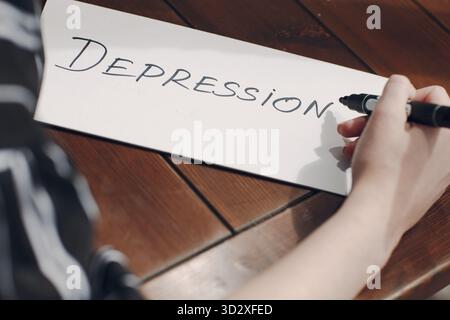 Donna mano scrittura parola depressione su foglio bianco Foto Stock