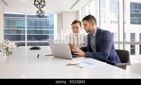Due colleghi caucasici che parlano al portatile Foto Stock