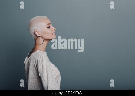 Giovane donna milleniale con capelli biondi corti profilo ritratto sognando Foto Stock