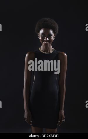 Ritratto sorridente di donna afroamericana con acconciatura afro su sfondo nero Foto Stock
