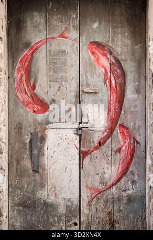 Pizzo, Italia â€“ 22 settembre 2025: Murale di Street art di pesce rosso dipinto su un'antica porta in legno nel centro storico di Pizzo, Calabria, Italia meridionale. Foto Stock