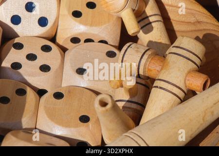 Una vista ravvicinata di dadi di legno artigianali e piccoli giocattoli in una ciotola presso un mercato artigianale locale. Le superfici lisce e lucide e le forme giocose si riflettono Foto Stock