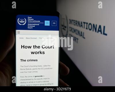 Stoccarda, Germania - 10-30-2025: Persona che detiene il cellulare con pagina web dell'organizzazione Tribunale penale internazionale (ICC) sullo schermo davanti al logo. Foto Stock