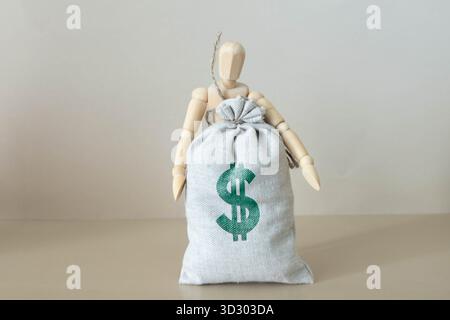 Uomo che tira su una corda un sacco di soldi, un muro grigio sullo sfondo. Foto Stock