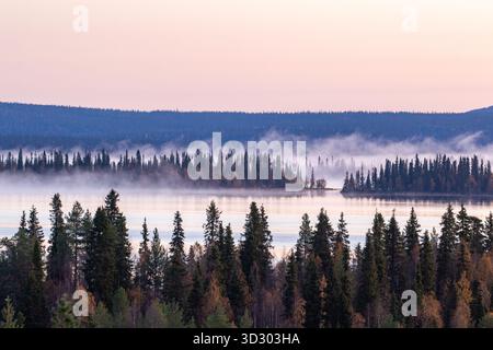 La nebbia si innalza lentamente sul lago presto in una fredda mattina autunnale nella Finlandia settentrionale, nell'Europa settentrionale Foto Stock