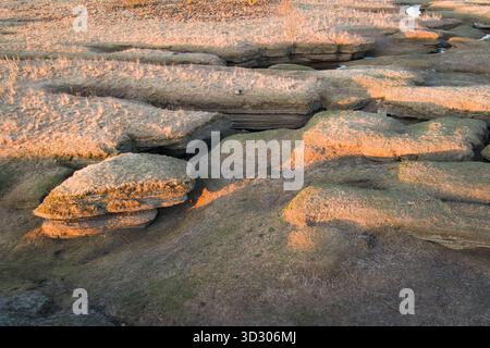 Vista aerea con droni di un paesaggio carsico all'inizio della primavera in Estonia, con formazioni rocciose a strati illuminate dalla calda luce del tramonto. Foto Stock
