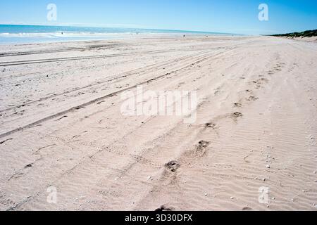 Vasta distesa sabbiosa di 80 Mile Beach nell'Australia Occidentale, con gomme e piste per piedi sotto un cielo azzurro e un mare turchese Foto Stock