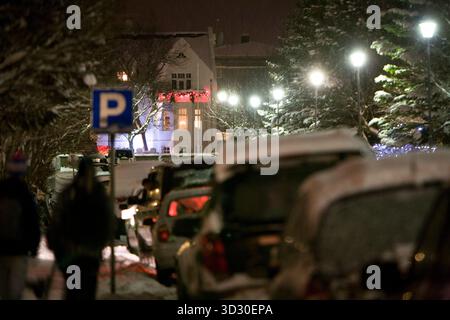 Persone che camminano durante una nevicata, auto parcheggiate. Centro di Reykjavik, Islanda Foto Stock