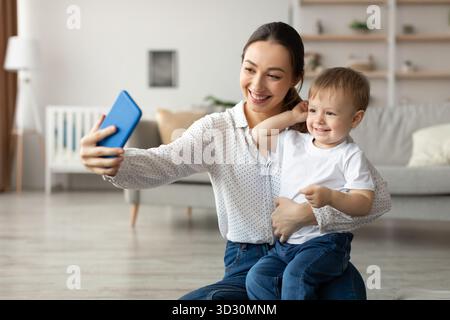 Madre e figlio condividono un momento di gioia per immortalare un selfie a casa durante un pomeriggio di sole Foto Stock