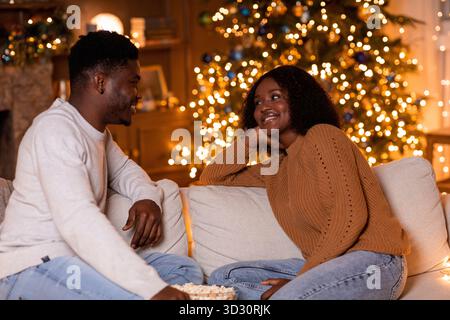 La giovane coppia gode di un'accogliente serata di film a casa con Popcorn e Holiday Spirit Foto Stock