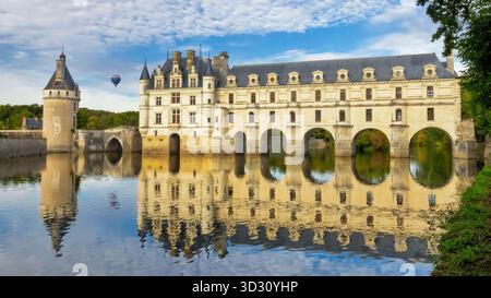 Uno splendido Chateau de Chenonceau si erge maestosamente su un riflettente fiume Cher, creando una visuale simmetrica. Il cielo blu e cl sparso Foto Stock