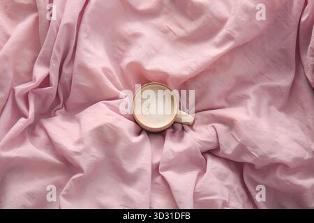 Tazza di caffè su lenzuola rosa Foto Stock