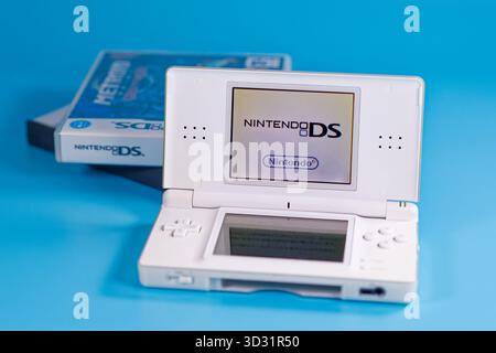 Fukuoka, Giappone - 4 novembre 2025: nintendo DS con varie cartucce di gioco isolate su sfondo blu Foto Stock