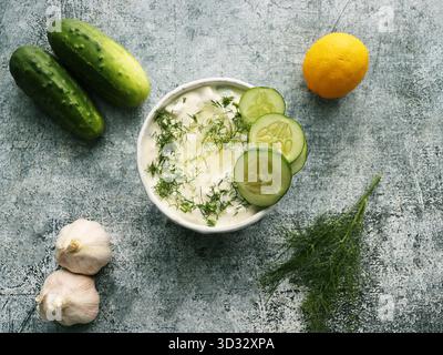 Salsa greca tradizionale o condimento tzatziki preparata con cetriolo grattugiato, yogurt panna acida, olio d'oliva e aneto fresco Foto Stock