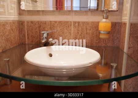 Bagno moderno con finiture eleganti, area lavandino pulita e organizzata con piastrelle calde Foto Stock
