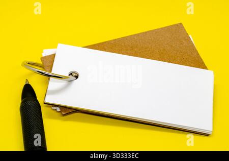 Blocco note bianco a forma di striscione con spazio personalizzabile per il testo su sfondo giallo con penna nera Foto Stock