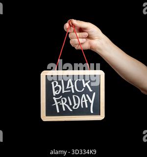 La mano di un uomo regge un piccolo cartello con scritto "Black Friday", isolato su uno sfondo nero puro Foto Stock